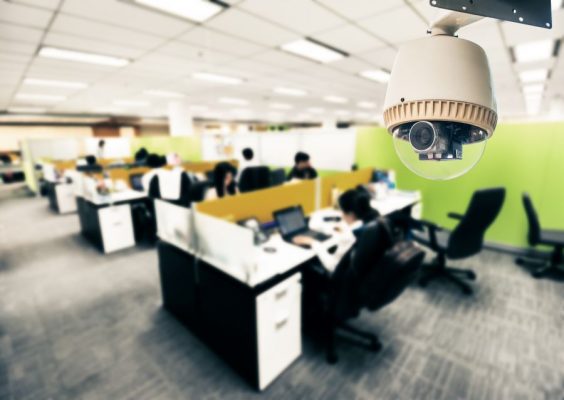 A security camera watching over an office with people at their desks.