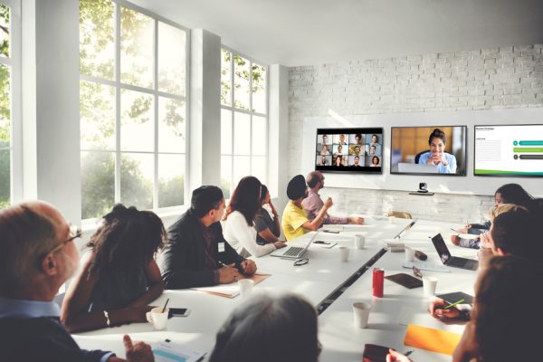 A large meeting space with people participating in a video conference.
